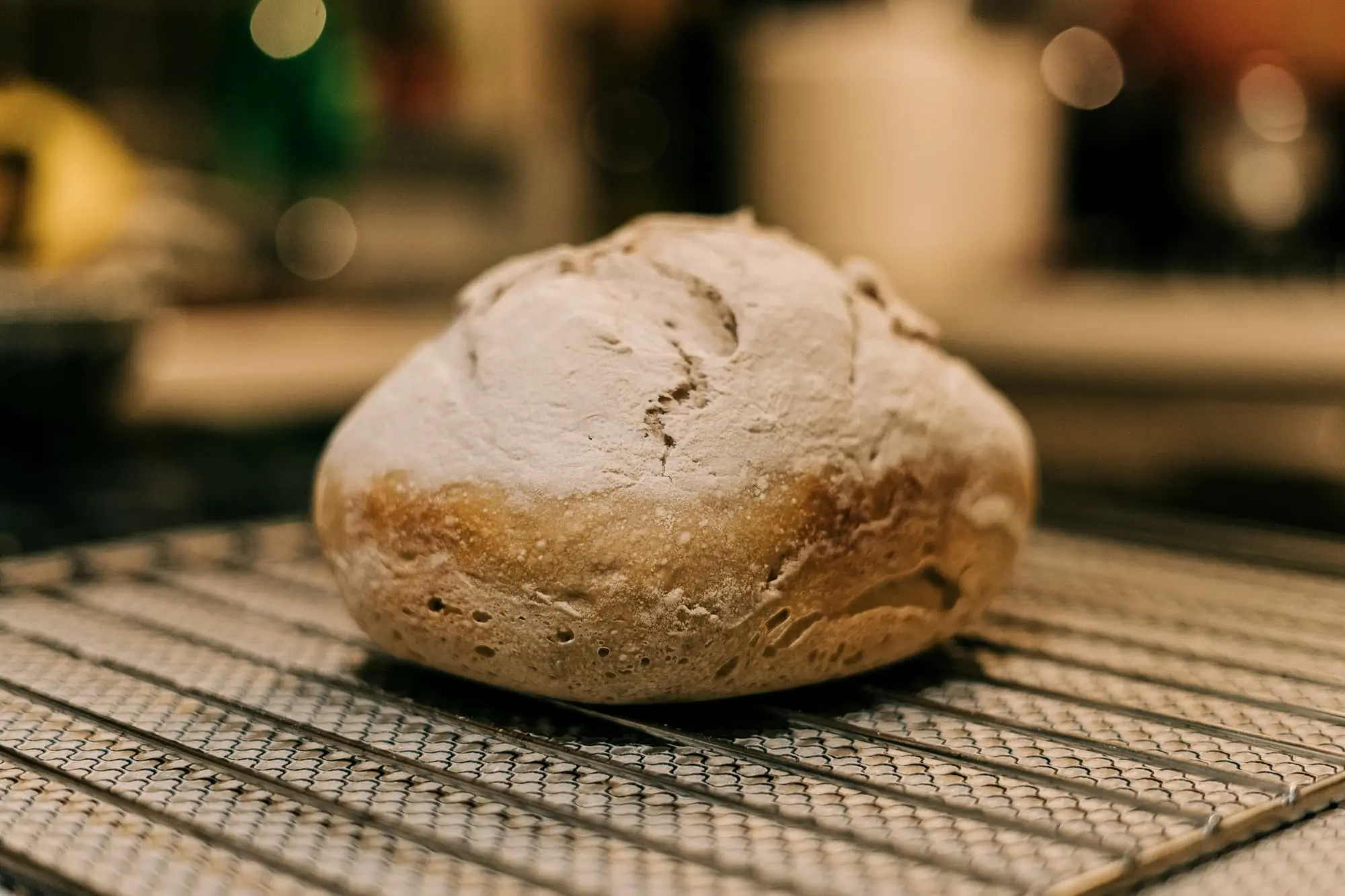 A round floured loaf cooling on a wire rack