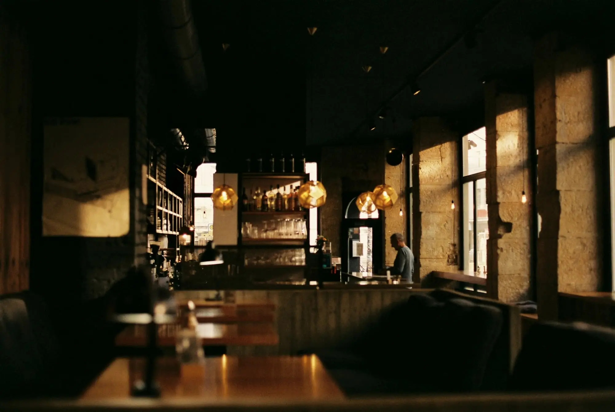 A long dim dining room with amber lit windows along one side