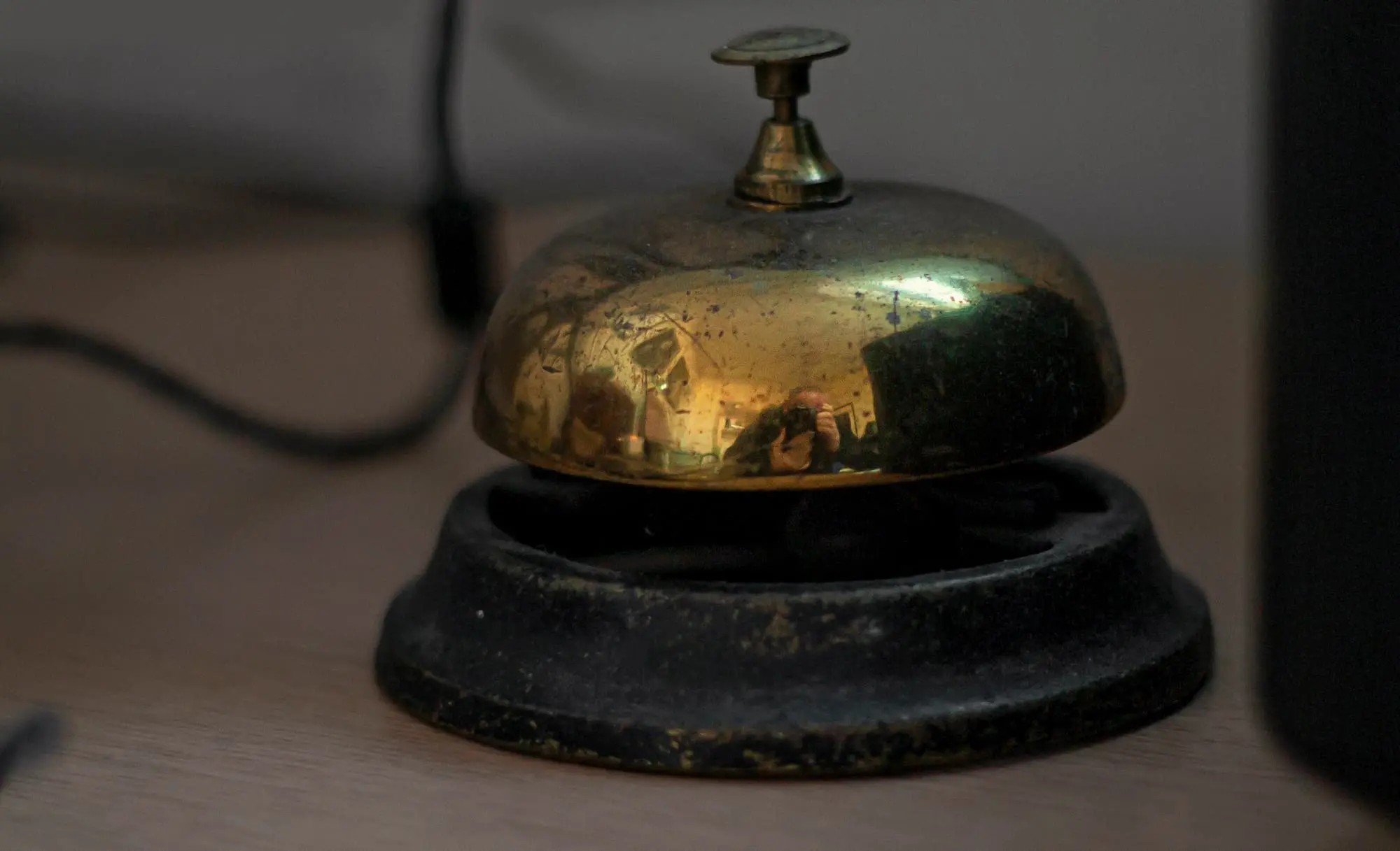 An old brass service bell on a wooden desk