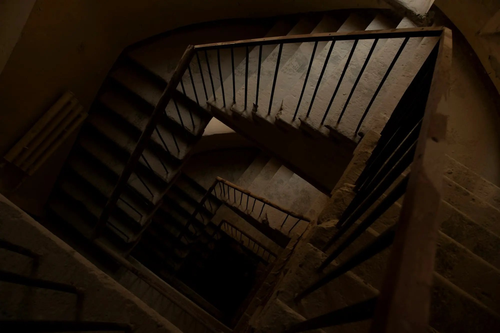 Looking down the well of a timber stair in brown shadow