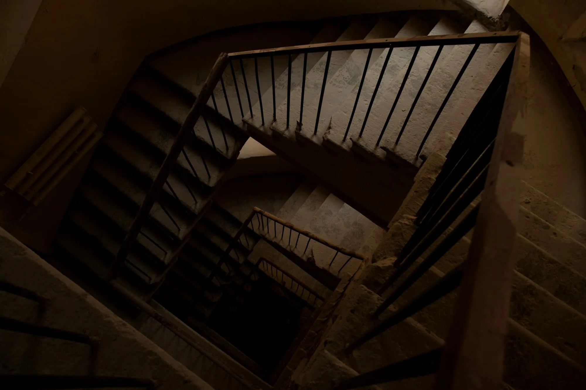 Looking down the well of a timber stair in brown shadow