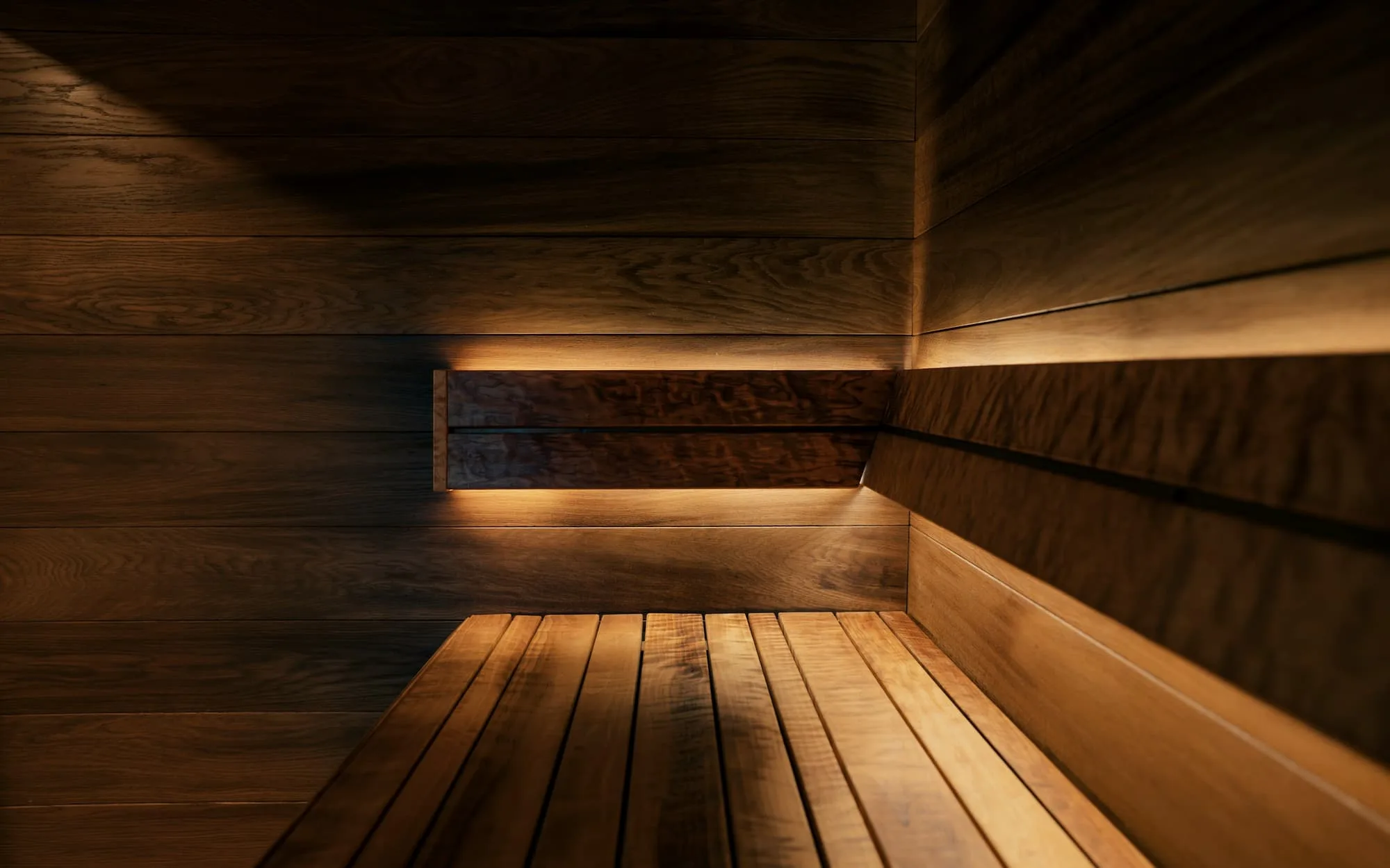 Timber sauna benches lit by a low line of warm light